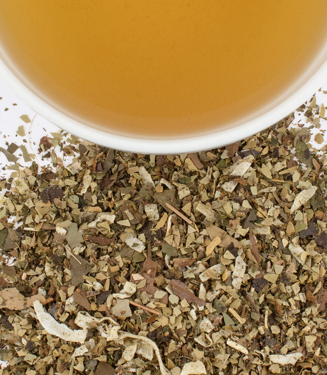 Yerba mate blend with yaupon and mint, featuring a cup of brewed tea above loose herbal ingredients.