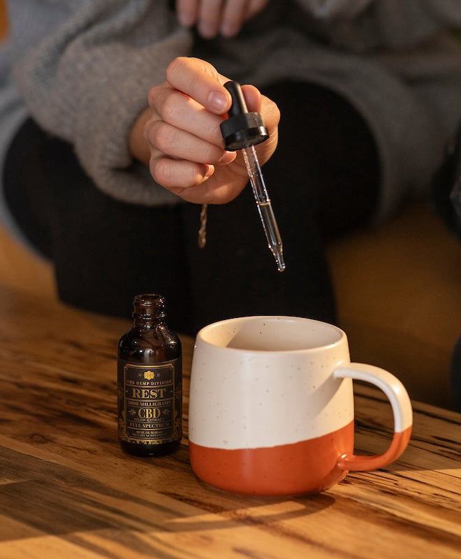 The Rest Tincture adding to a cup of hot tea.