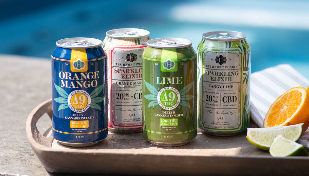 Four cans of different flavors on a tray with a pool in the background.