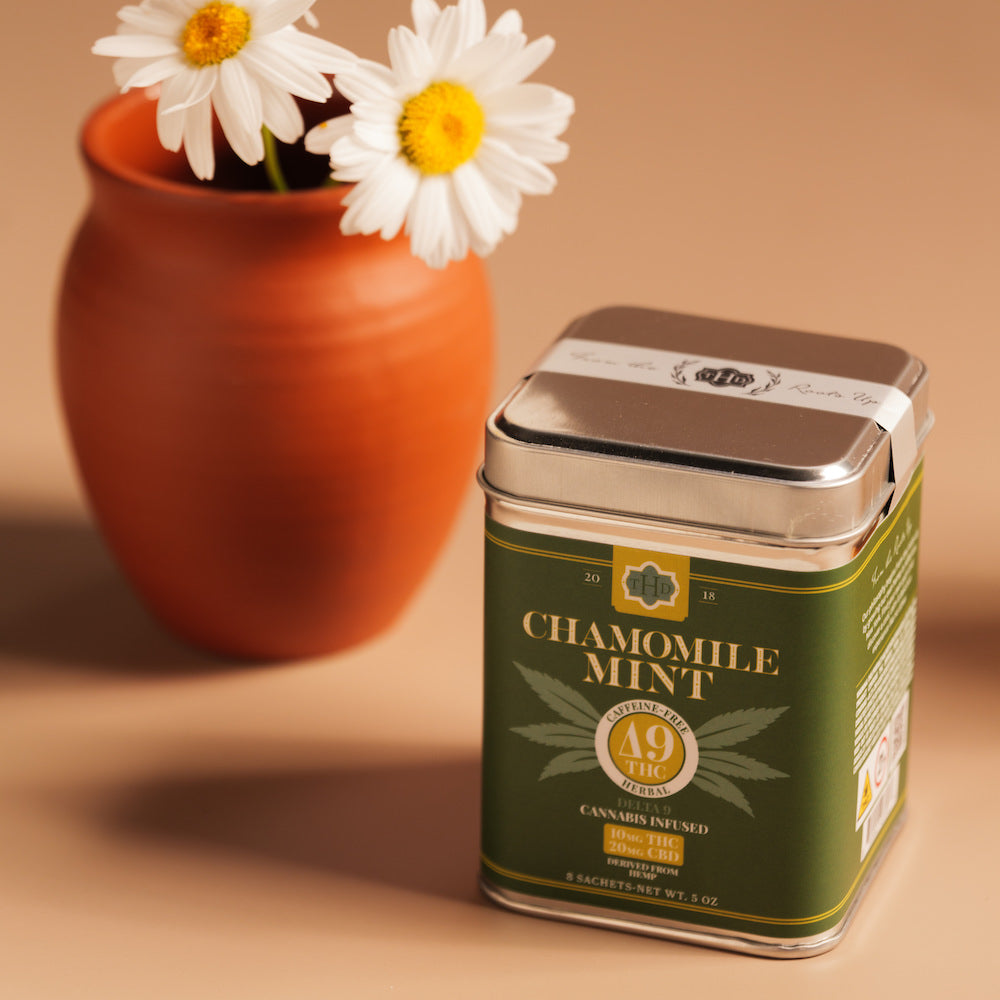 Chamomile Mint Delta 9 tea tin on table next to a vase with flowers.