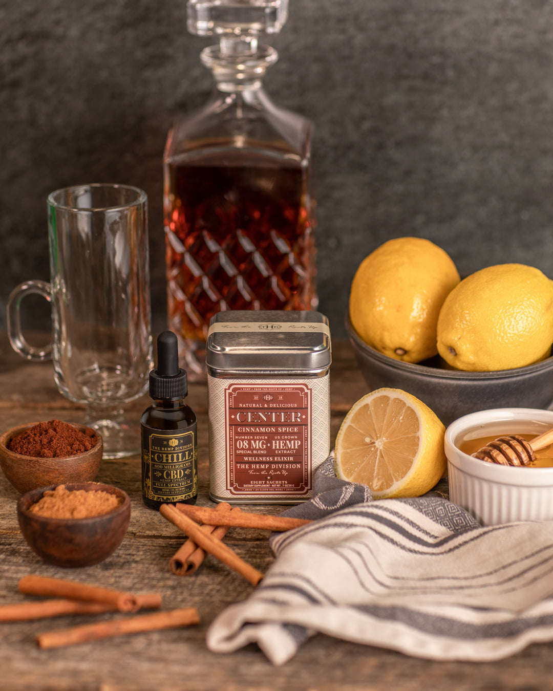 Cinnamon Spice CBD product with honey, lemons, and spices on a rustic wooden table.