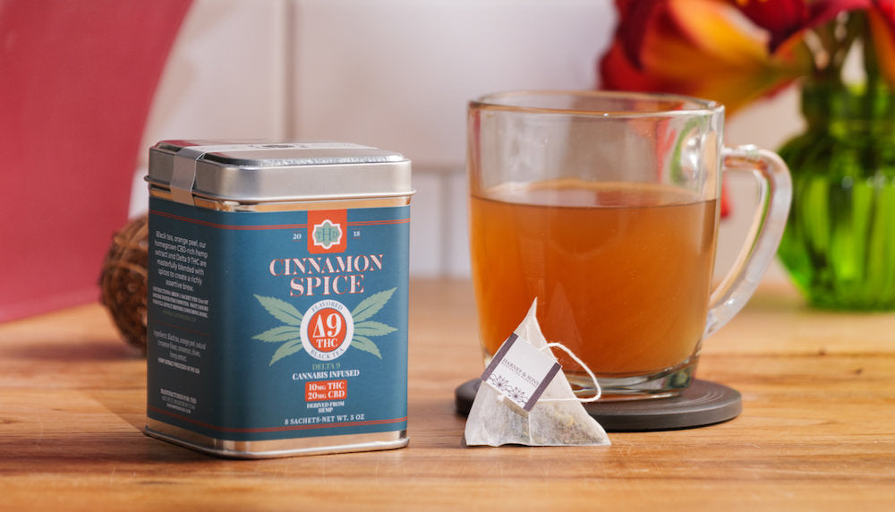 Cinnamon Spice tea canister with a glass of tea on a wooden table