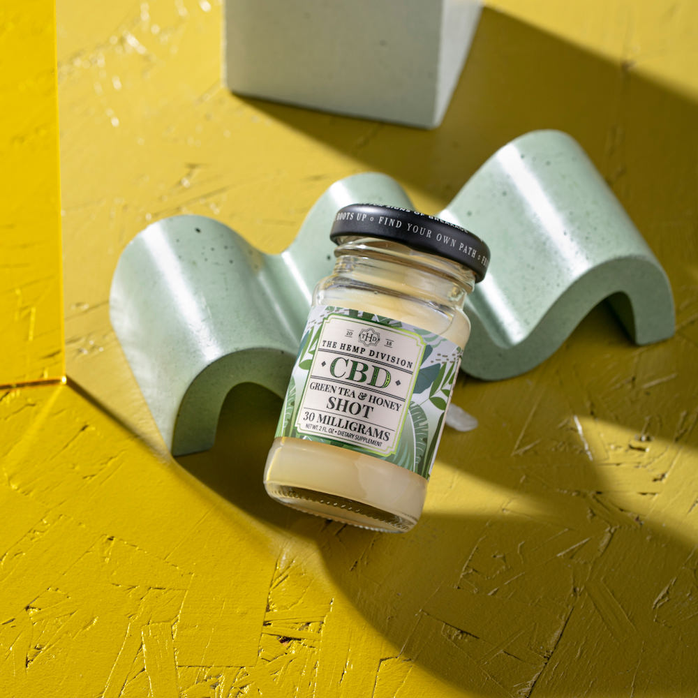 CBD Green tea & honey shot lying on a decorative table.